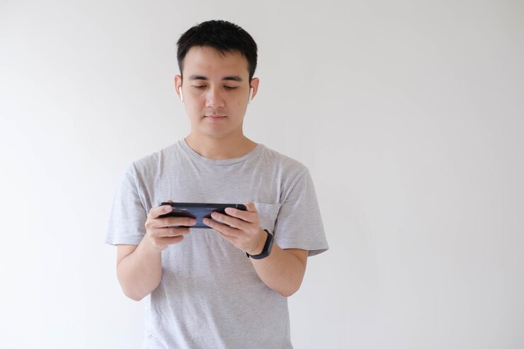 Un joven asiático está jugando en el teléfono inteligente