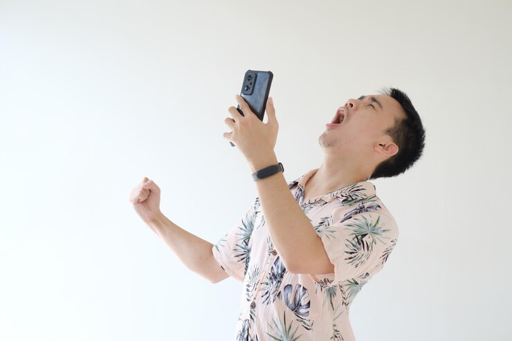 El joven asiático está muy feliz y emocionado mientras sostiene su teléfono inteligente