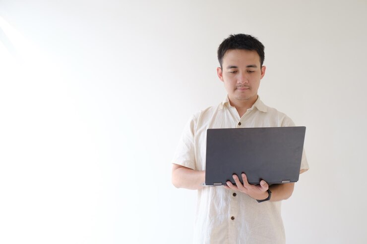 Joven asiático está usando una computadora portátil negra que resiste