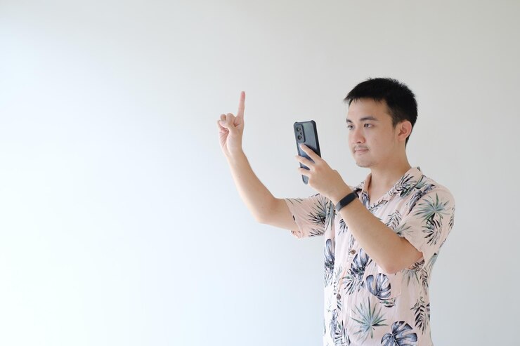 Un joven asiático fotografiando usando un teléfono inteligente y su dedo indicó uno