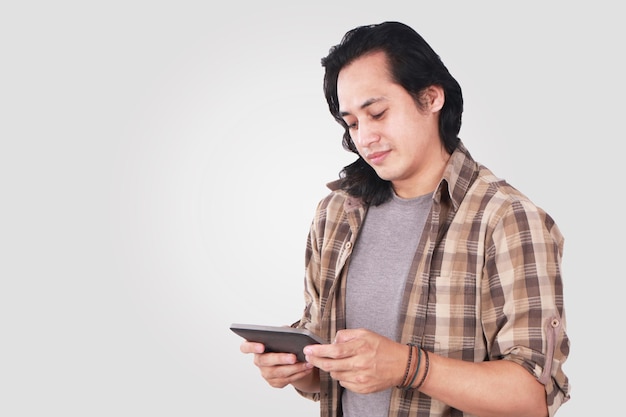 Un joven asiático gracioso jugando a juegos en la tableta.