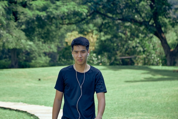 Joven asiático guapo haciendo ejercicio en el parque con un rastreador de fitness