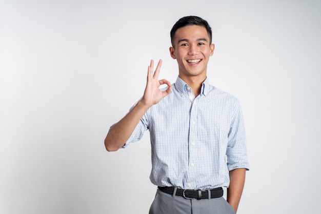 Joven asiático mostrando gesto de mano bien con una sonrisa