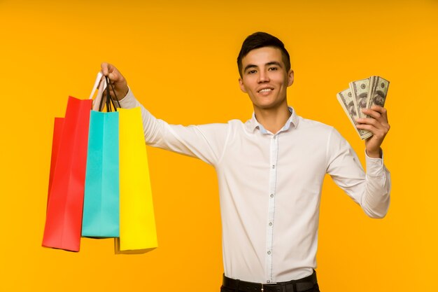 Joven asiático mostrando su bolsa de compras y dinero