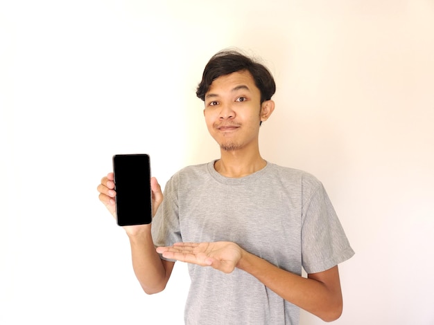 Joven asiático mostrando teléfono inteligente con pantalla en blanco