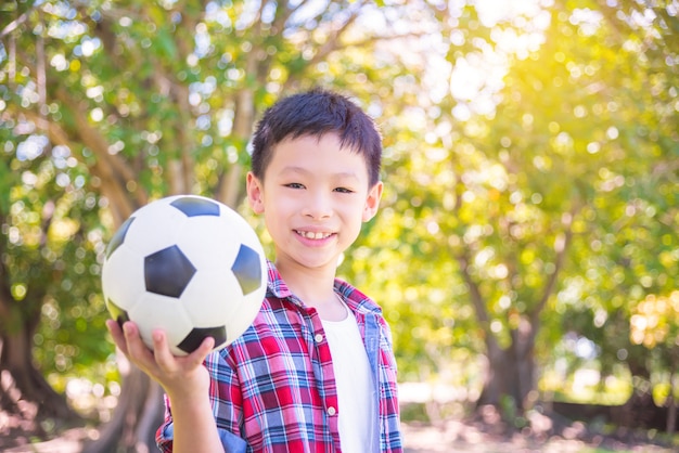 Joven asiático con pelota en el parque