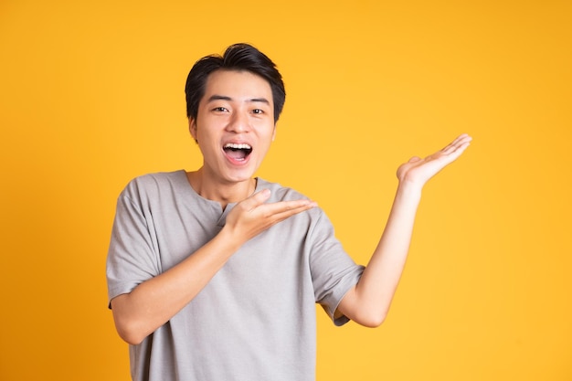 Joven asiático posando sobre un fondo amarillo