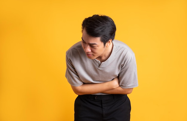 Joven asiático posando sobre un fondo amarillo