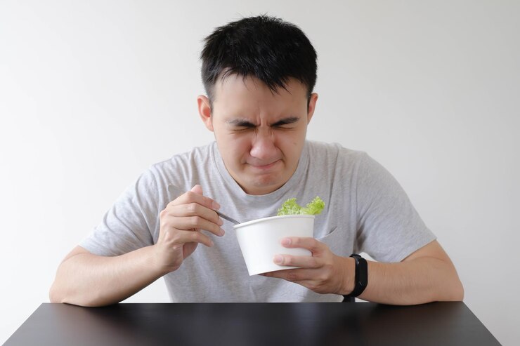 Un joven asiático reacciona al sabor de la comida frunciendo el ceño