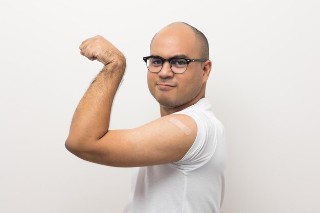 Foto joven asiático recibió una vacuna corona retrato de un hombre asiático que muestra su hombro con una venda después de recibir una protección de vacunación contra el coronavirus en un fondo blanco aislado