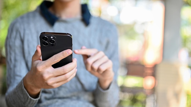 Un joven asiático con ropa informal usando su teléfono inteligente tocando la pantalla de su teléfono