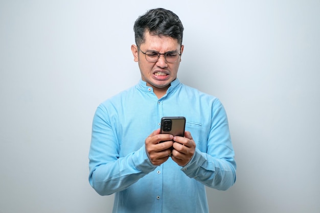 El joven asiático se siente enojado mirando el teléfono inteligente