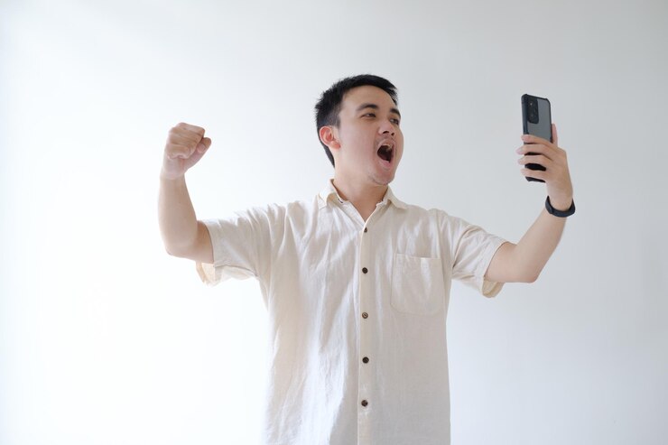 Un joven asiático se siente feliz mientras mira su teléfono inteligente