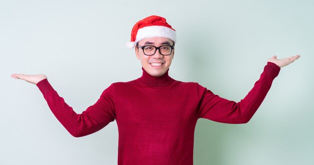 Joven asiático con sombrero de Navidad sobre fondo verde