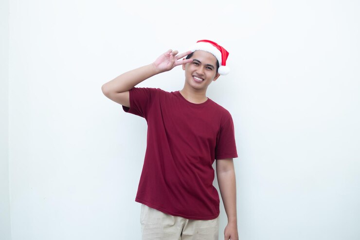 Un joven asiático con un sombrero de Papá Noel haciendo una señal de paz con dos dedos