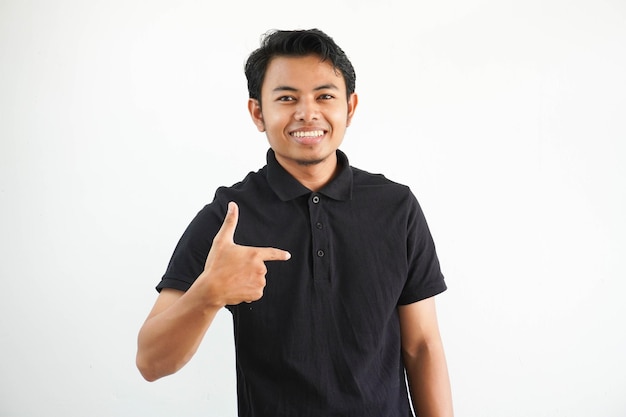 Foto joven asiático sonriente señalando a sí mismo con expresión emocionada usando una camiseta de polo negra
