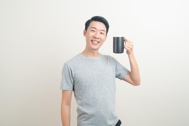 joven asiático sosteniendo una taza de café con cara sonriente sobre fondo blanco