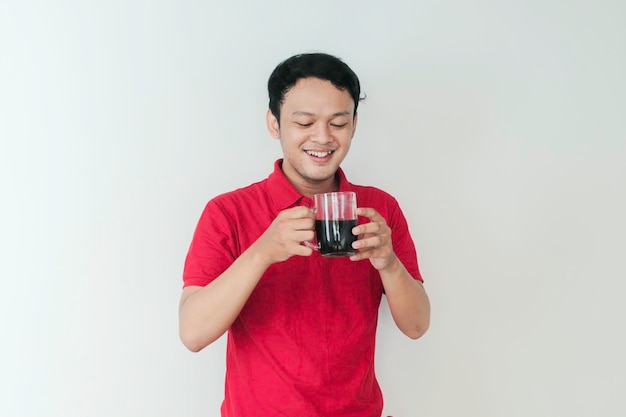 Joven asiático sosteniendo una taza de café de pie sobre un fondo blanco aislado feliz con una gran sonrisa