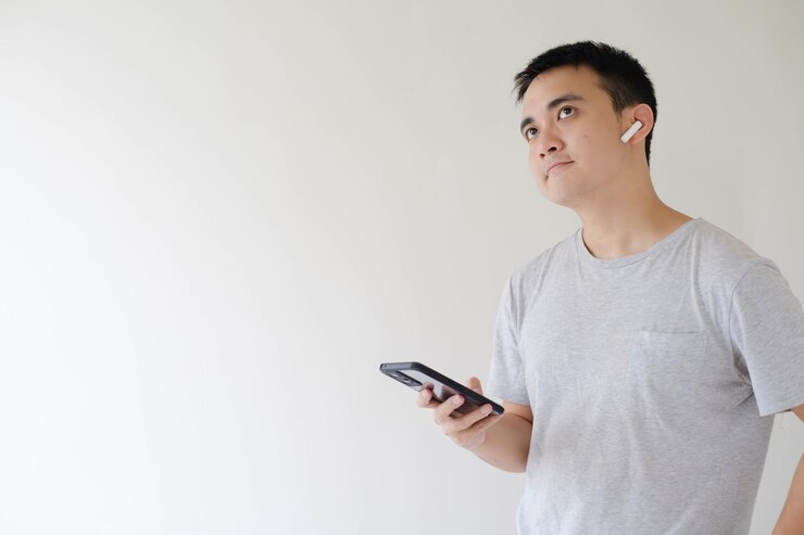 Un joven asiático sostiene un teléfono inteligente confundido