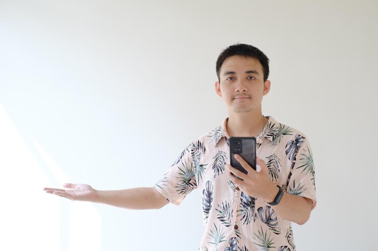 Un joven asiático sostiene un teléfono inteligente con la mano derecha abierta