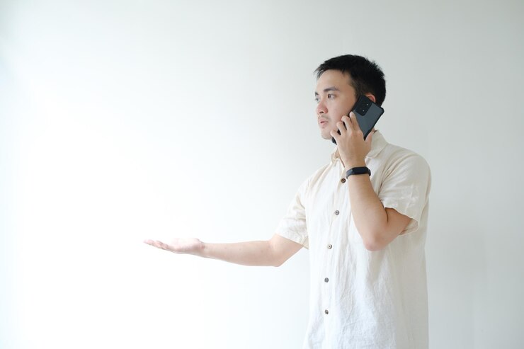 El joven asiático tiene la palma abierta en la mano derecha mientras llama al teléfono inteligente