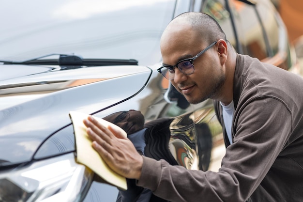 El joven asiático usa un paño de microfibra y pule para limpiar los autos y hacerlos brillar. Se ocupa de cada detalle del auto.