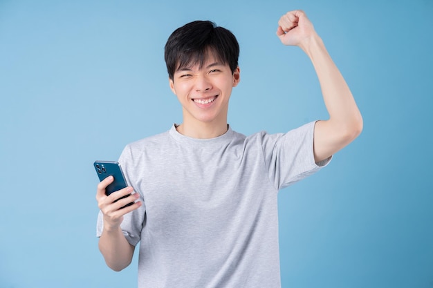 Joven asiático usando un teléfono inteligente con fondo azul