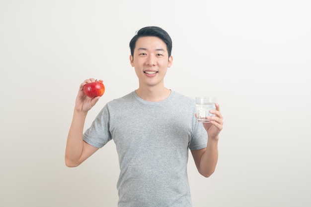 Joven asiático con vaso de agua y manzana a mano