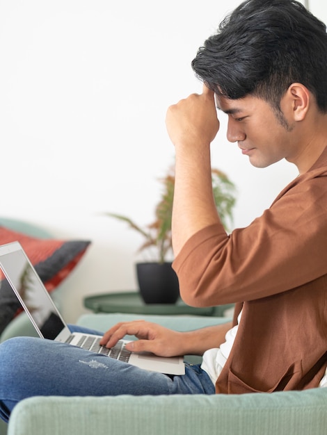 Joven asiático vistiendo ropa casual y con dolor de cabeza