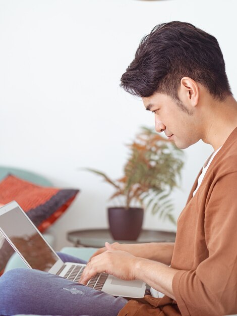 Joven asiático vistiendo ropa casual y usando laptop