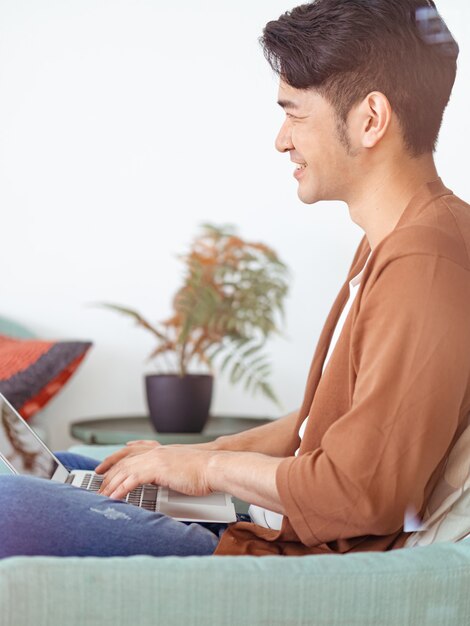 Joven asiático vistiendo ropa casual y usando laptop