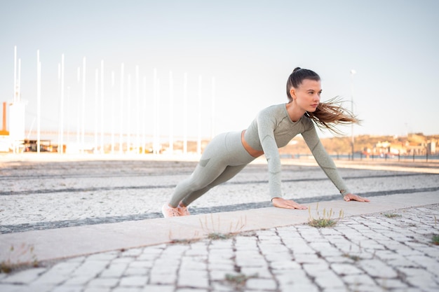 Joven atleta atractiva en ropa deportiva realizando flexiones en un paso concreto