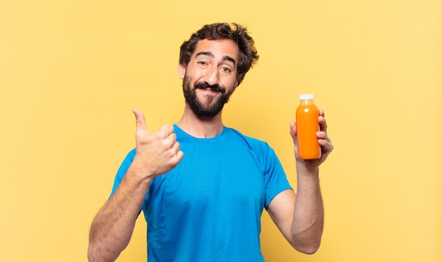 Joven atleta barbudo loco feliz expresión y sosteniendo un batido