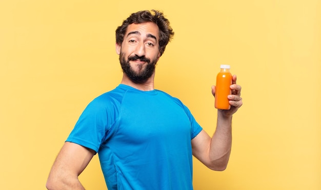 Joven atleta barbudo loco feliz expresión y sosteniendo un batido