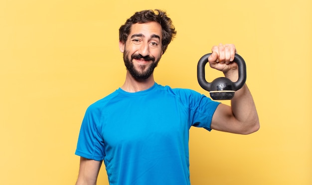 Joven atleta barbudo loco joven atleta barbudo loco expresión feliz y levantando una pesa