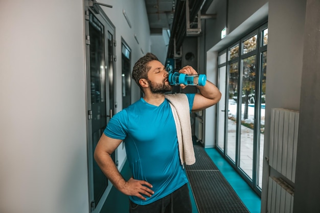 Joven atleta bebiendo agua después de un entrenamiento agotador