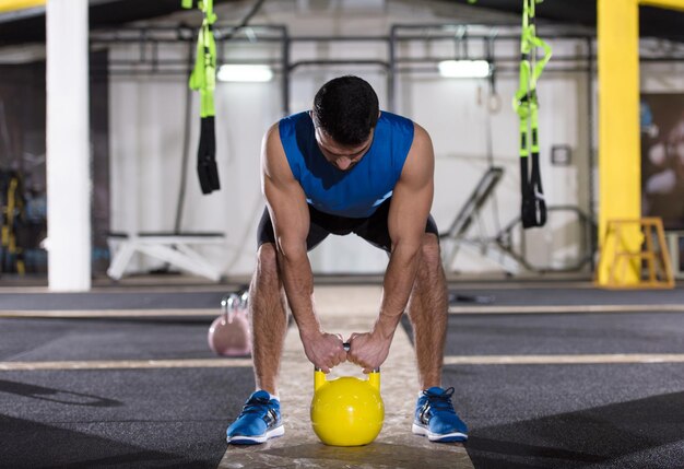 joven atleta ejercicio con pesas rusas en el gimnasio cross fitness