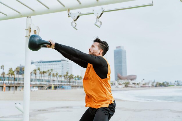 Joven atleta entrenando por la mañana en la playa en el gimnasio