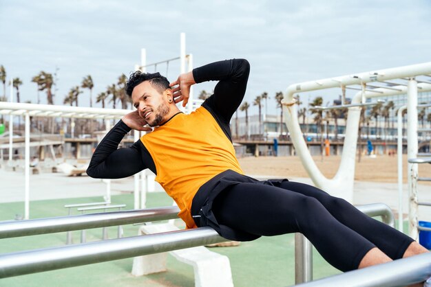 Joven atleta entrenando por la mañana en la playa en el gimnasio