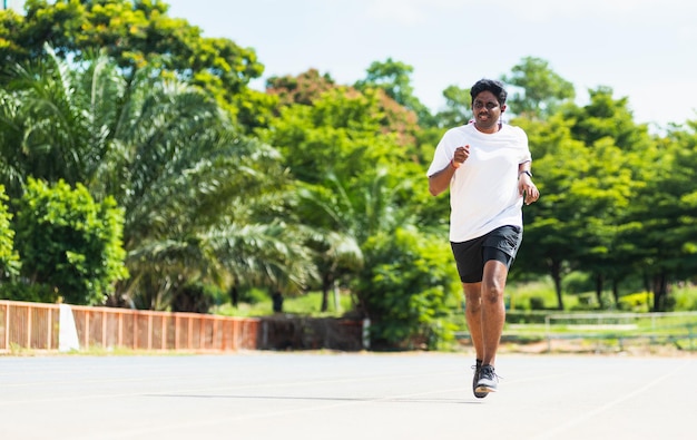 Joven atleta de estilo de vida asiático, corredor deportivo, hombre negro, usa zapatos de pies, entrenamiento de carrera activo al aire libre en la carretera de la línea de la cinta de correr, entrenamiento de ejercicio saludable