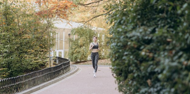 Joven atleta femenina activa ejercicio al aire libre en el otoño soleado
