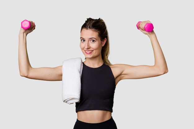 Joven atleta femenina levantando pesas enfocada y determinada en un estudio interior