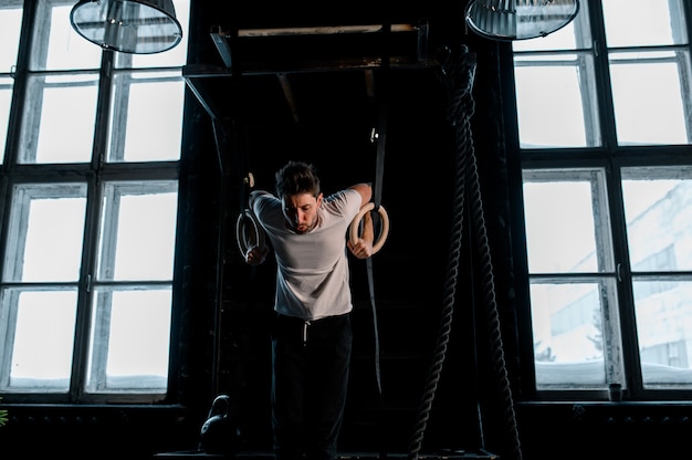 Joven atleta masculino con anillos de gimnasia en el gimnasio se centran en anillos foto de alta calidad