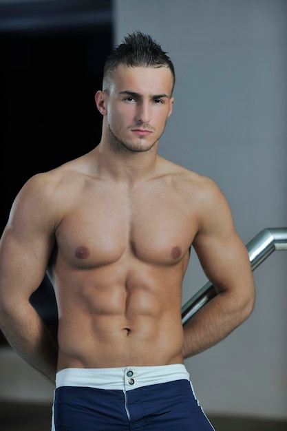 Joven atleta modelo de hombre macho guapo saludable en la piscina cubierta del hotel