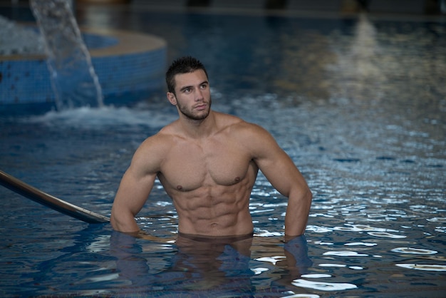 Joven atleta modelo de hombre macho guapo saludable en la piscina cubierta del hotel