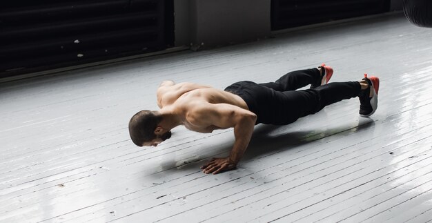 Joven atleta muscular haciendo flexiones de brazos en suspensión. Foto de alta calidad