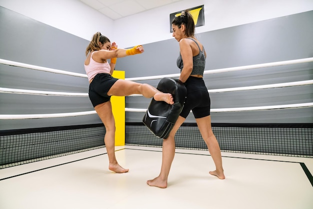 Joven atleta practicando kickboxing en un ring con su pareja en un gimnasio