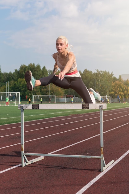 Joven atleta runner corriendo obstáculos en el estadio al aire libre