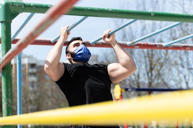 Foto joven atleta trabajando bíceps en un gimnasio al aire libre haciendo ejercicios de entrenamiento callejero