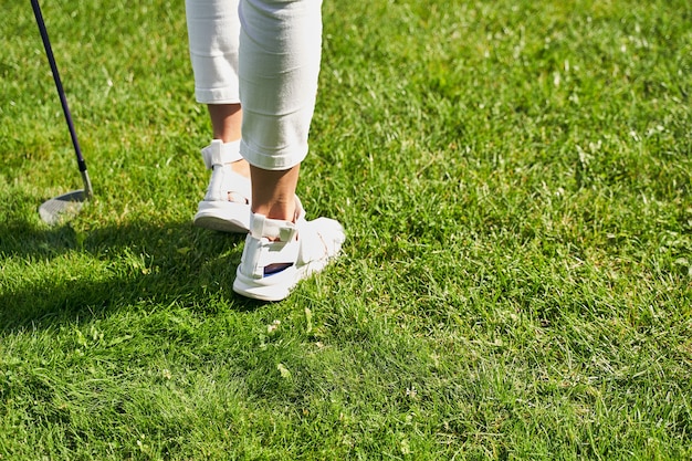 Una joven atleta en zapatos de golf de pie en el campo de prácticas